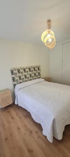 um quarto com uma cama branca e um lustre em Andreda em Burgos