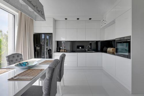 biała kuchnia ze stołem i krzesłami w obiekcie Grand Apartments - Apartament Tre Mare - By the sea w Gdańsku