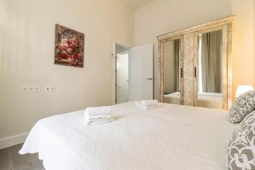 a white bed with two towels on top of it at Casa Palacio Rufina & Jardines in Jerez de la Frontera