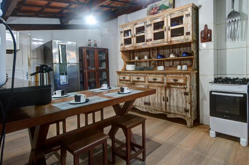 a kitchen with a wooden table and a refrigerator at Casarão Serenitá in Aquiraz