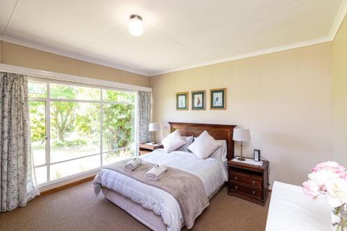 um quarto com uma cama e uma grande janela em Lowestoffe Country Lodge - Trout em Hogsback