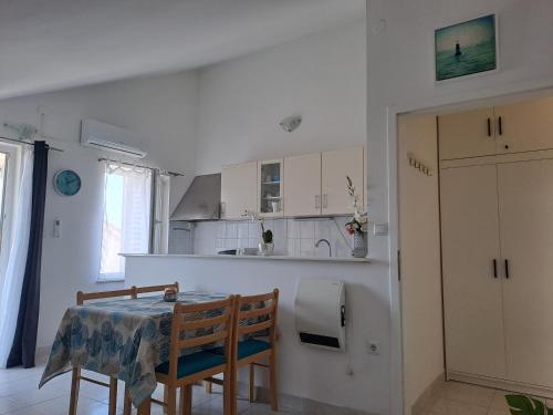 a kitchen with a table and two chairs and a table and a kitchen at Son de Mar Novalja-Pag Apartment in Novalja