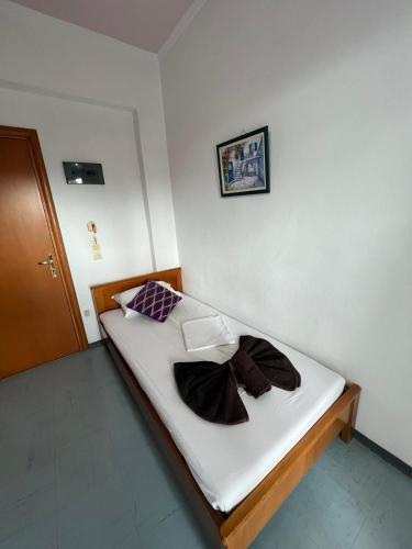 a small bed with white sheets and a brown bow on it at Faliro Hotel in Faliraki