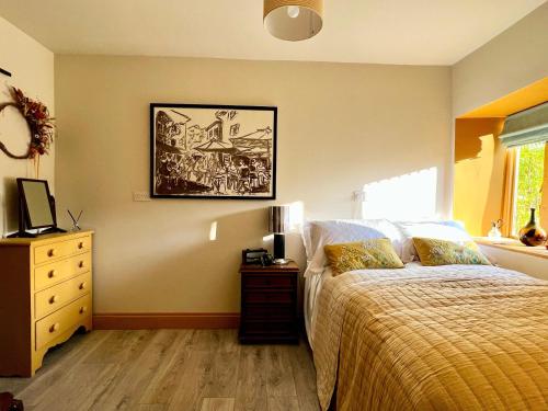 a bedroom with a bed and a dresser and a picture at Eclectic Barn - Pergola & Dog-Friendly Garden in Calne