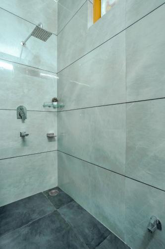 a bathroom with a shower with white walls at SaffronStays Kesar Villa, Manali - beautiful villa amidst an apple orchard - All clear roads in Manāli