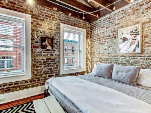 Un dormitorio con una pared de ladrillo y una cama en Broughton Corner Loft en Savannah