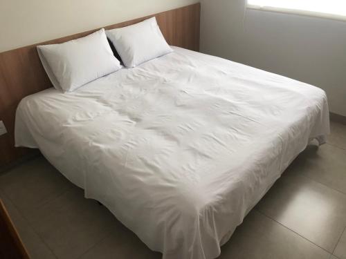 ein großes weißes Bett mit zwei Kissen darauf in der Unterkunft Vêneto Flat Residence (AP-11) in Primavera do Leste