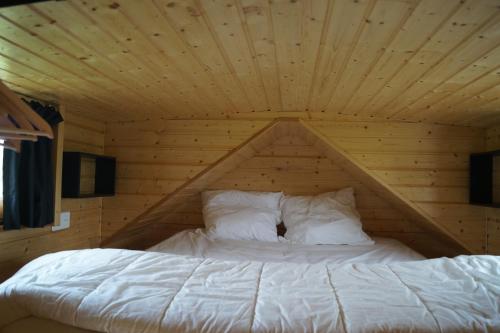 a bed in a room with a wooden ceiling at Spa & Bain Nordique - Tiny house à la campagne in La Boissière