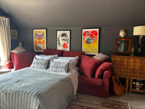 a bedroom with a bed and a couch and paintings at Eclectic Barn - Pergola & Dog-Friendly Garden in Calne