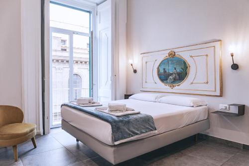a white bedroom with a large bed and a chair at La Smorfia in Naples