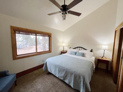 a bedroom with a bed with a ceiling fan and a window at Columbine B Cabin Suite in Woodland Park