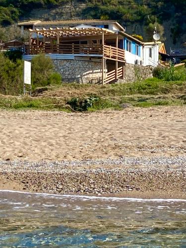 a house on the beach next to the ocean at Hamre Apartments (Nicholas) in Agios Georgios Pagon