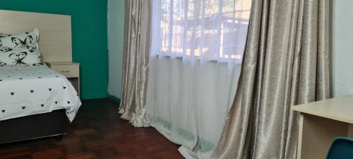a bedroom with a bed and a window with curtains at Ojong's Court Bellville in Cape Town