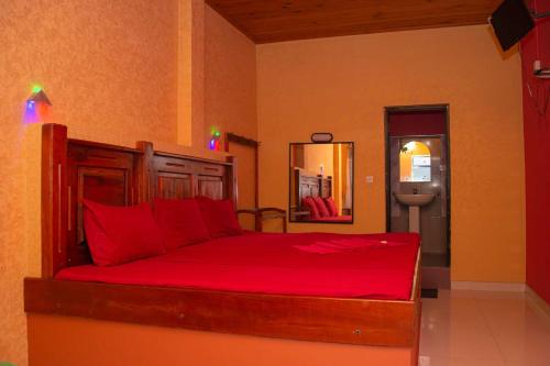 Schlafzimmer mit einem Bett mit roter Bettwäsche und einem Spiegel in der Unterkunft Hotel Janara in Kurunegala