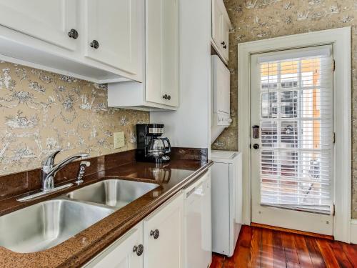 a kitchen with white cabinets and a sink at Bird Baldwin Parlor in Savannah