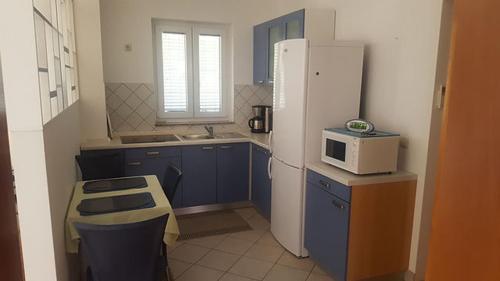 a kitchen with blue cabinets and a white refrigerator at Apartment Cizici ,Best Place 100m zum Meer, Soline bay, insel-krk,de in Čižići