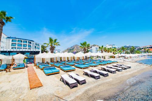 a group of lounge chairs and umbrellas on a beach at Class Unique Beach in Marmaris