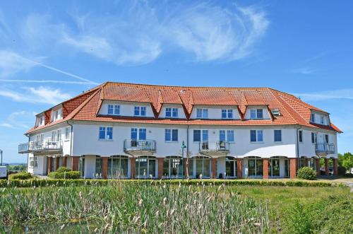 a large white building with an orange roof at DEB 040 Ferienwohnung Jasmund in Neddesitz