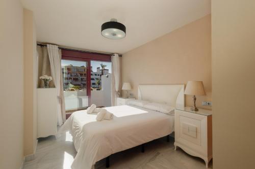 una camera bianca con un letto e una finestra di Apartment, with indoor pool, jacuzzi, sauna and gym, in Benahavis a Estepona