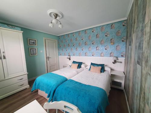 1 dormitorio con 2 camas y pared azul en Casa Marcela en Gijón