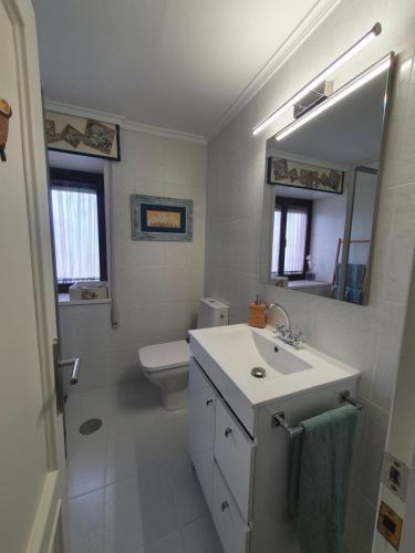y baño con lavabo, aseo y espejo. en Casa Marcela en Gijón