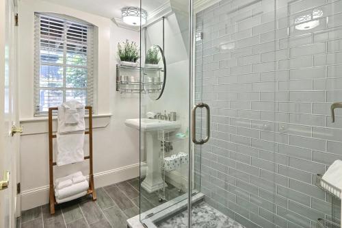 La salle de bains est pourvue d'une douche en verre et d'un lavabo. dans l'établissement Under The Red Door On Monterey, à Savannah