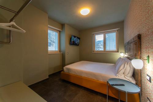um quarto com uma cama, uma mesa e 2 janelas em CityU - Milano 25 Appartamento Trento Centro con parcheggio privato em Trento
