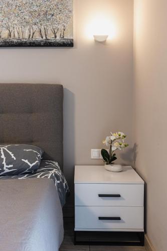 a bedroom with a bed and a white nightstand with flowers on it at Aura Home in Dnipro