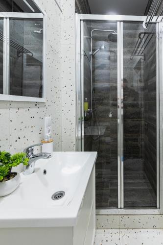 a bathroom with a white sink and a shower at Aura Home in Dnipro