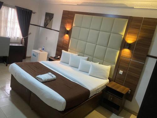 a bedroom with a large bed with a large headboard at Presken Hotel @Villa in Ikeja