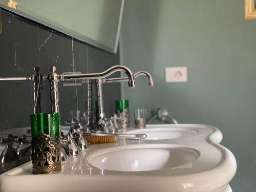 a bathroom with two sinks with green cups on it at Burlamacchi Villas in Bagni di Lucca