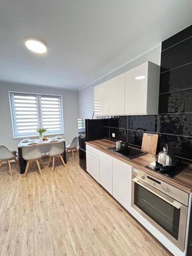 a kitchen with white cabinets and a table and a dining room at Apartamenty Kalisz Pomorski in Kalisz Pomorski
