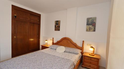 een slaapkamer met een bed met een houten hoofdeinde en 2 lampen bij Sea Apartment 4082 in Torrevieja