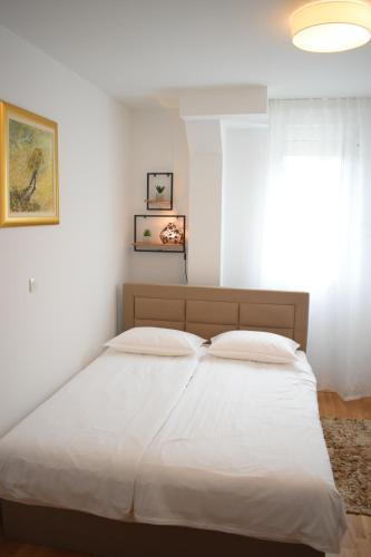 Una cama con sábanas blancas y una ventana en un dormitorio en Apartment Aria Split, en Split