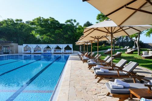 a swimming pool with lounge chairs and umbrellas at Carmel Forest by Isrotel Exclusive in Bet Oren