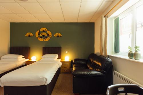a hotel room with two beds and a leather couch at The Imperial Dragon Hotel in Saundersfoot