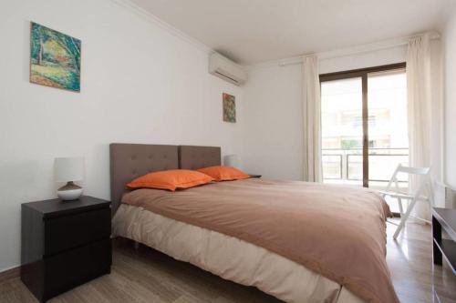 1 dormitorio con 1 cama con almohadas de color naranja y ventana en 2-bedroom 2 min from the beaches with a terrace, en Cannes