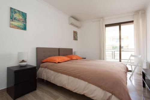 une chambre avec un lit avec des oreillers orange et une fenêtre dans l'établissement 3-Room Apartment with Terrace in Palm Beach, à Cannes