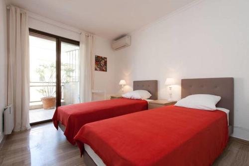 two beds in a room with a window at 2-bedroom 2 min from the beaches with a terrace in Cannes