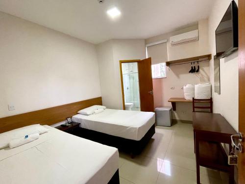 a hotel room with two beds and a desk at Nav Park Hotel in Naviraí