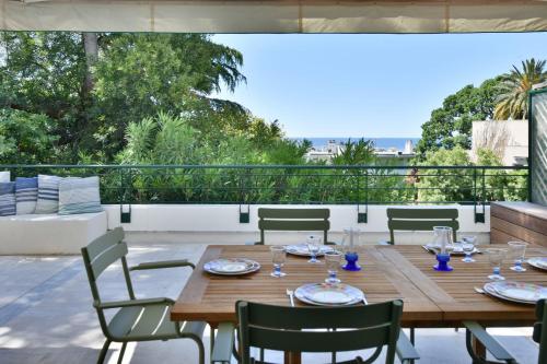une table et des chaises en bois sur une terrasse dans l'établissement Stunning 3-Br Apartment with Large Terrace and Pool, à Cannes