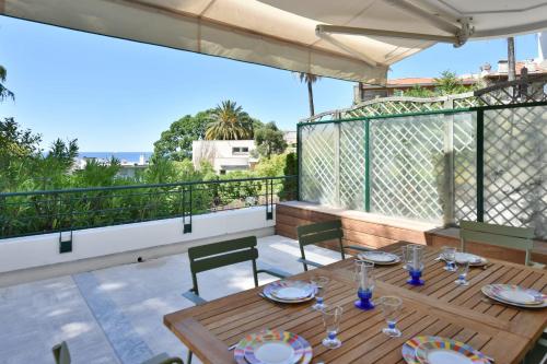 d'une terrasse avec une table et des chaises en bois sur un balcon. dans l'établissement Stunning 3-Br Apartment with Large Terrace and Pool, à Cannes