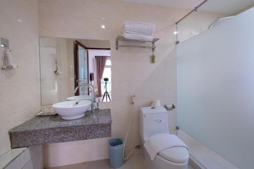een badkamer met een wastafel, een toilet en een spiegel bij Zuka Hotel & Apartment in Da Nang