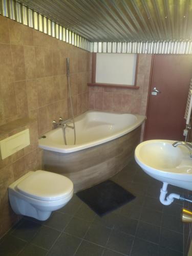 a bathroom with a tub and a toilet and a sink at Guesthouse Maddy in Húsavík