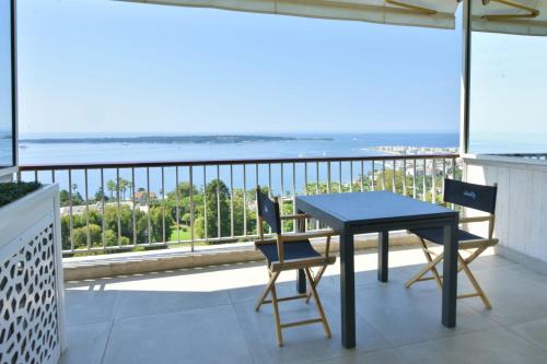 a table and chairs on a balcony with a view of the ocean at Apartment in a 8 hectares park incredible view in Cannes