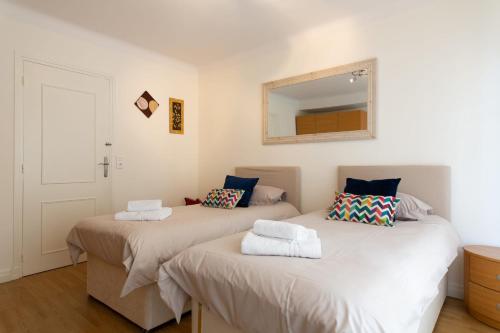 - 2 lits dans une chambre avec un miroir mural dans l'établissement 2-Br Apartment 2 min from the Beaches, à Cannes