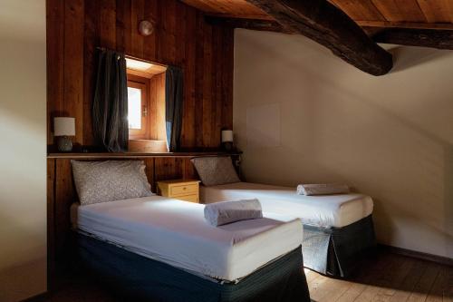 two twin beds in a room with a window at Visaisa taverna & foresteria in Acceglio