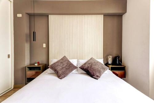 a bedroom with a white bed with two pillows at Loft moderno en Barranco con piscina vista al mar in Lima
