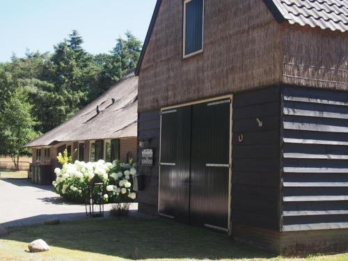 a barn with a door and flowers in front of it at Schaapskooi in Dwingeloo