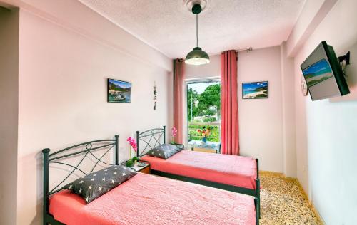 two beds in a room with a window at Arilena Studios in Paralia Saranti